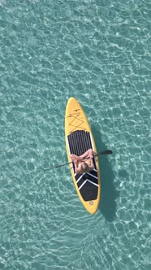 Aerial View of Caucasian Woman on Paddleboard Floating in the Crystal Clear Sea