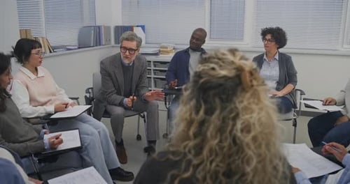 Inside Training Room Adult Participants Gather in Seated Circle While Instructor Leads Conversation