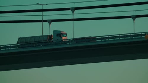 White transportation truck driving on a suspended bridge, close up tracking shot, blue clear sky in