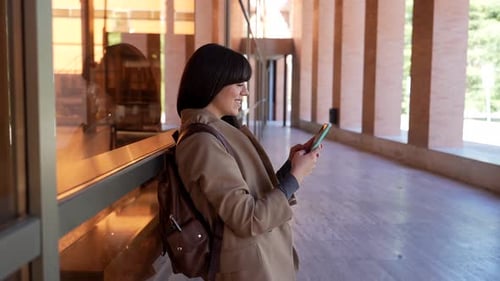 University student using smartphone and smiling at camera