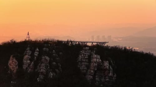 Mountain Viewpoint Structure Overlooking Hazy City at Sunset