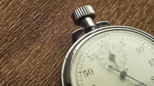 Weiße Vintage-Stoppuhr auf braunem strukturiertem Hintergrund dreht den Pfeil