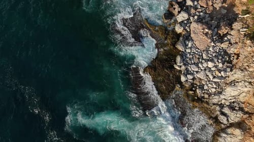 Aerial View on Ocean Waves Crashing and Foaming Around a Huge Stone Cliffs Nea