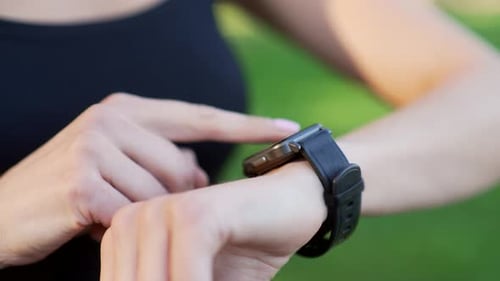 Close up of a female hand with a smart watch. Sportswoman uses a fitness tracker, scrolls her finger