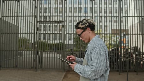 Gen Z Asian Man Using Tablet Walking along City Street
