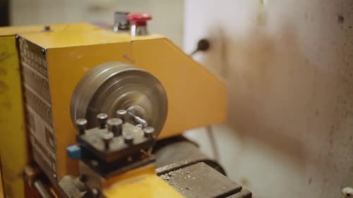 Close up of old dusty Turning lathe in action, cutting off a layer of a metal bar in old workshop.