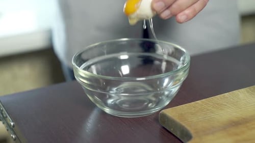 Adding a Fresh Egg to a Clear Bowl