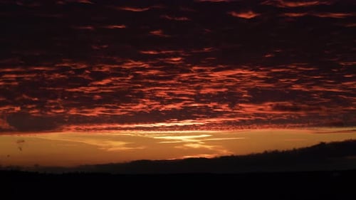 Dramatic red sunset reflecting on cloud blanket in nature, time lapse
