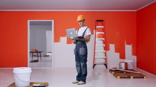 Full Body Of Side View Asian Man Painter Using A Laptop With Painting Wall In Room