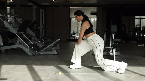 Fitness Woman Diligently Performing Lunges in a Stylish and Modern Gym