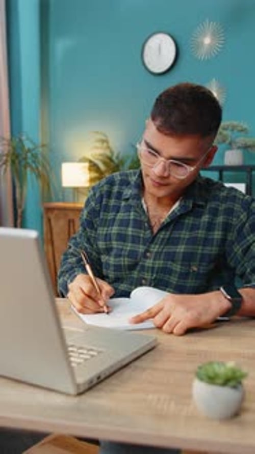 Young Adult Student Writing in Notebook at Desk