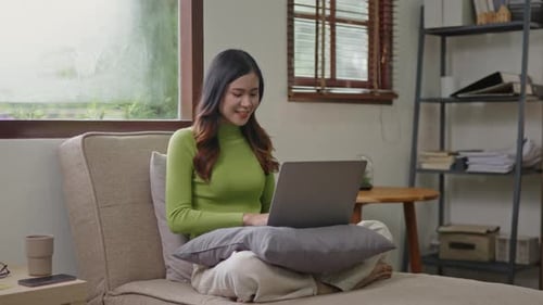 Woman wears green sweater working studying and liniving at home.