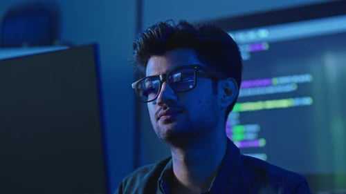 Programador com reflexão de interface em óculos no escritório noturno