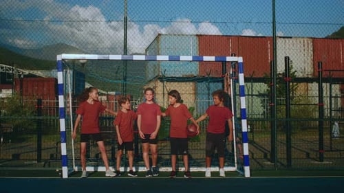 Young Football Team Players Stand in Line in Front of Goal and Embrace on Courtyard Sports Field