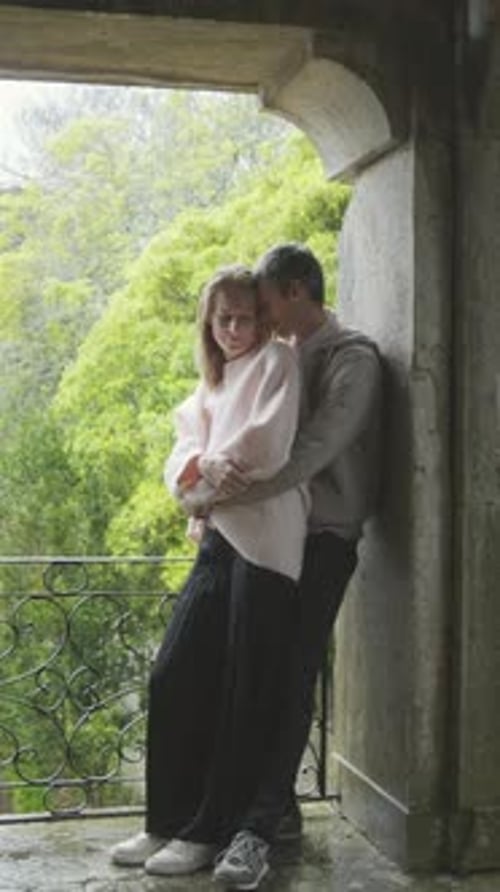 Romantic Couple Embracing on Balcony of Historic Building