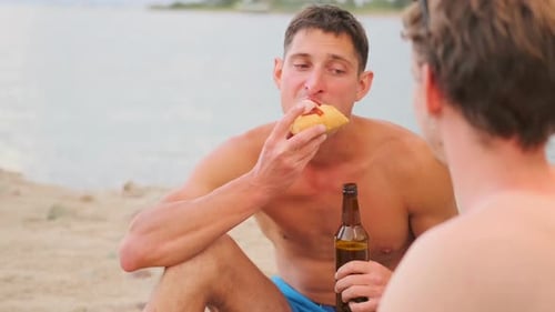 Romantisches Date mit zwei Schwulen beim Frühstück am Strand, ohne Hemd mit Bier und Hotdogs.