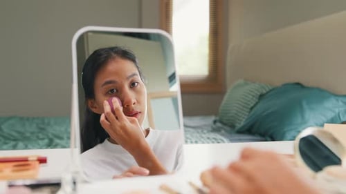 Woman Applying Make-Up in Bedroom Mirror