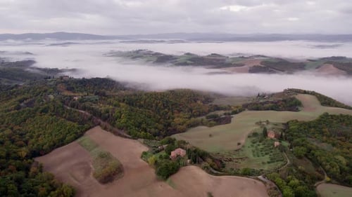 Aerial view of foggy sunrise over countryside with villa, Italy.