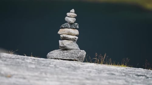 A balanced rock cairn stands on a flat rock, creating a peaceful and meditative scene in the wildern