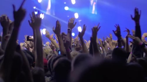 People with hands up at the rock concert, view with stage lights