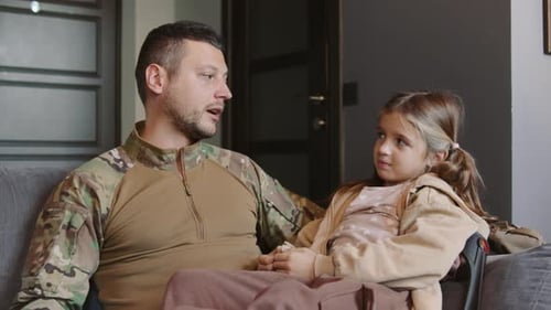 Man in uniform talks to young girl on couch