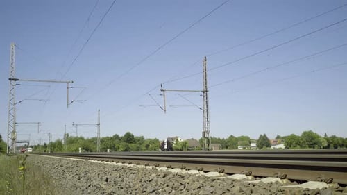 ICE-Hochgeschwindigkeitszug, der auf Gleisen in sonniger ländlicher Umgebung vorbeifährt, strahlend blauer Himmel über uns, Dyna