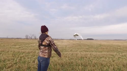 Woman Releasing Snowy Owl into Rural Field