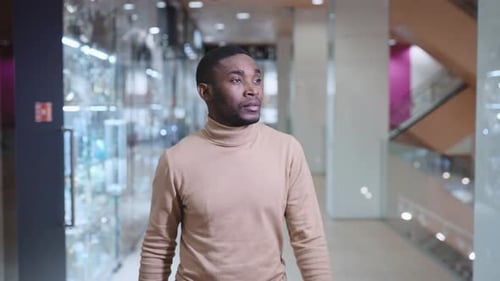 A Young African Man is Walking Through the Mall