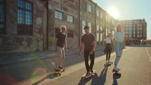 Group of Girls and Boys on Skateboards Ride Through Fashionable Hipster District. Beautiful Young