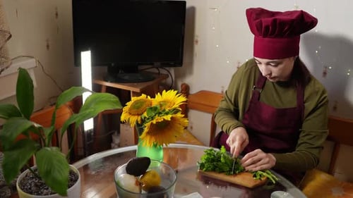 Woman Wearing Red Apron and Hat is Chopping Fresh Green Parsley Filmed in Slow Motion