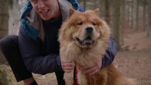 Man Hugging a Chow Chow Dog in Forest