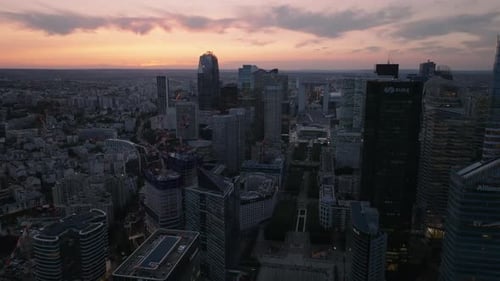 Backwards Fly Above Modern Business Urban District at Dusk High Rise Office Towers Against Colorful
