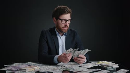A Man in a Suit and Glasses Counting Money and Dropping It in Disappointment