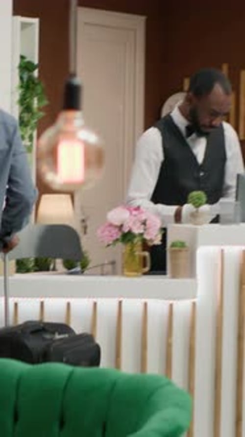 Hotel Guest Arrives at Reception Desk with Luggage