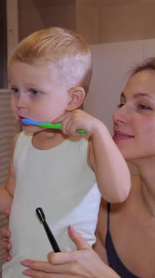 Parent and Child Brushing Teeth Together in Bathroom