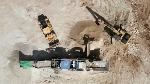 Bucket loader loading Gravel onto an Articulated hauler Truck trailer at a large construction site
