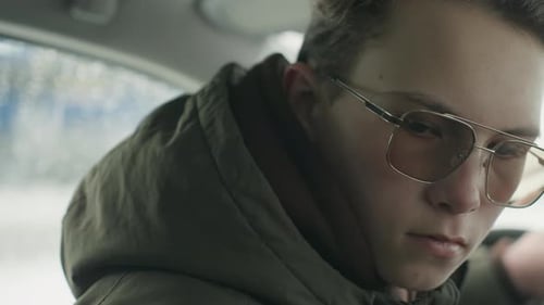 Young Adult Smiling in Car on a Rainy Day