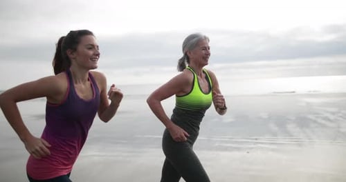 Mother and Daughter Jogging Along the Ocean Beach