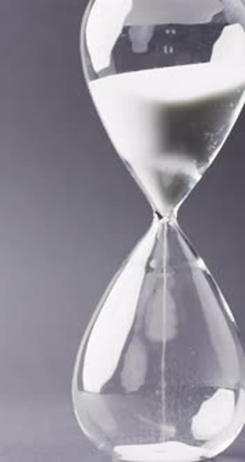 Vertical video of hourglass with sand pouring, copy space on black background