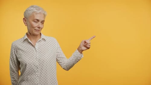 Mature Woman Point At Copy Space Gesture on Yellow