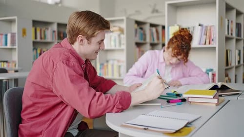 Freshmen Do Research Together Sitting at Desk in Library