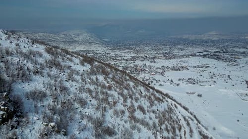 Aerial View of Winding Highway Through Snow-Covered Mountains