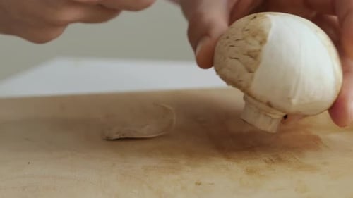 Personne épluchant des champignons sur une planche à découper, gros plan