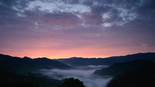 The sun rose at the top of the mountain as the orange-red clouds turned grey.