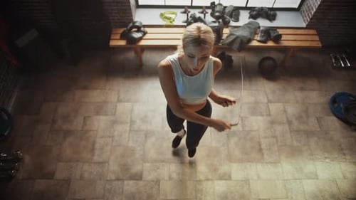 Athletic Beautiful Woman Wearing Sportswear Exercises with Skipping Rope in the Hardcore Gym. Fitne