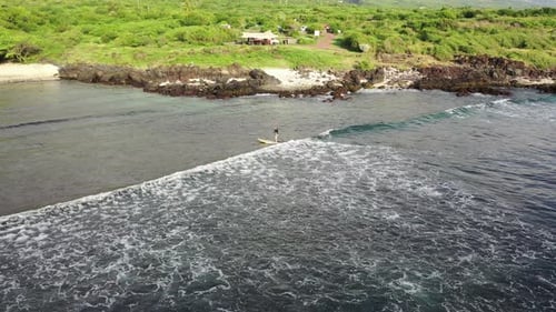 A paddleboarder surfs a wave on a on sup board in the ocean in the waters of Reunion Island