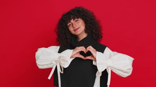 Woman Making Heart Shape Gesture on Red Background