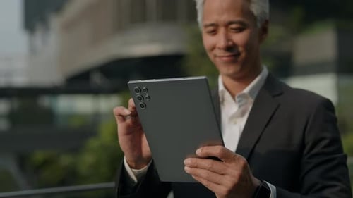 Smiling Man in Suit Using Tablet Outside