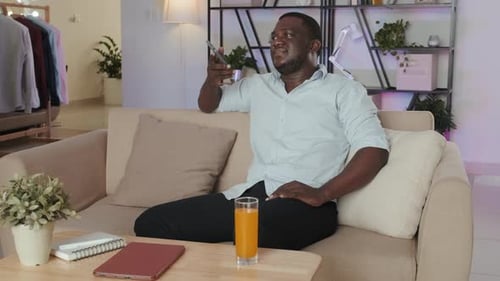 Man Relaxes on Couch Using Smartphone at Home