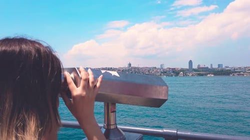 Woman Looks Through Binoculars at Distant City
